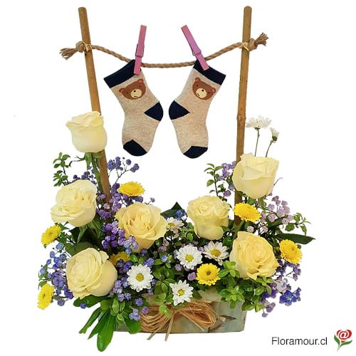 Imagen de un arreglo floral para recién nacidos con rosas y flores de complemento en un marco de bambú con calcetines de bebé Arreglo floral único y original para celebrar la llegada del nuevo miembro de la familia Incluye rosas frescas flores de complemento adorables calcetines de bebé y un marco de bambú rústico que sirve como colgador de ropa